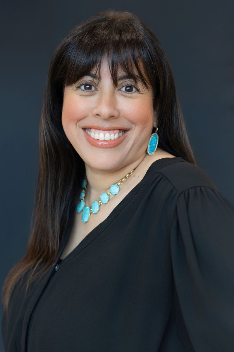 Holly Subervi smiling in a black blouse and turquoise necklace