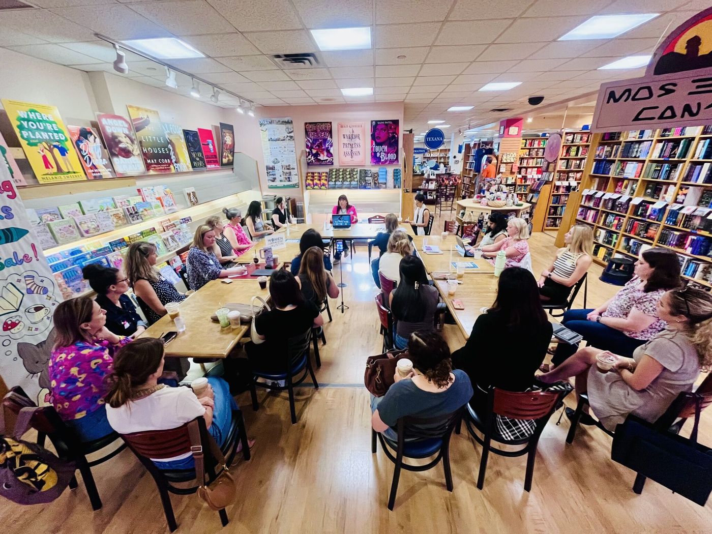 Holly Subervi leading a discussion with a room of women seated around tables in a bookstore