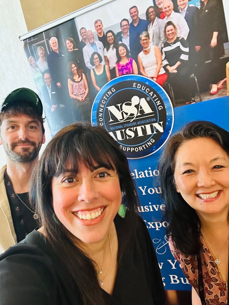 Holly Subervi taking a selfie with two NSA Austin members in front of the chapter banner